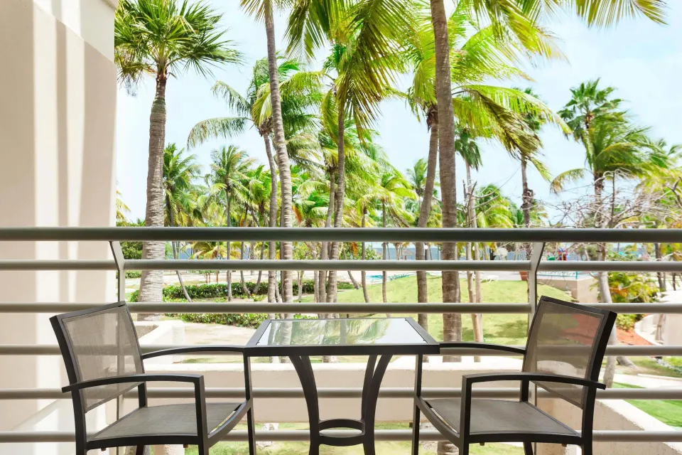 Furnished balcony with palm and pool views at Hilton Ponce Golf & Casino Resort.