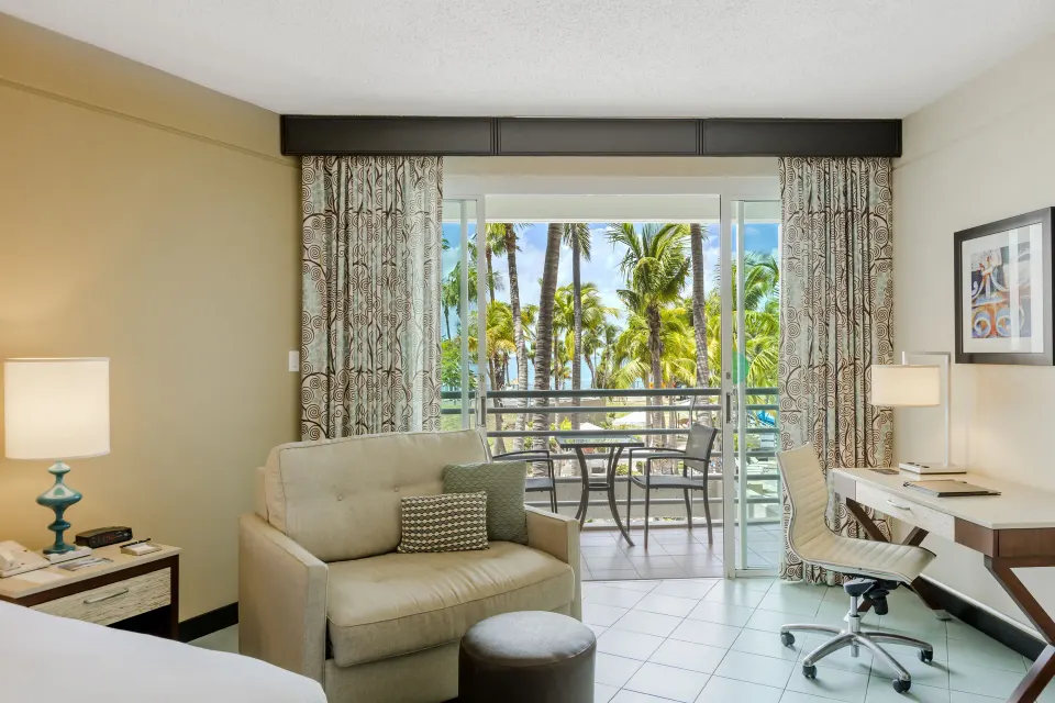 Sitting area and balcony in a pool view room at Hilton Ponce Golf & Casino Resort.