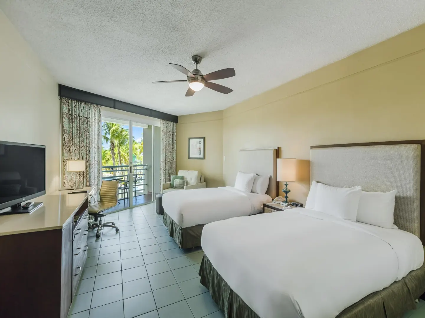 Two-bed balcony pool view room at Hilton Ponce Golf & Casino Resort with TV, desk, and balcony.