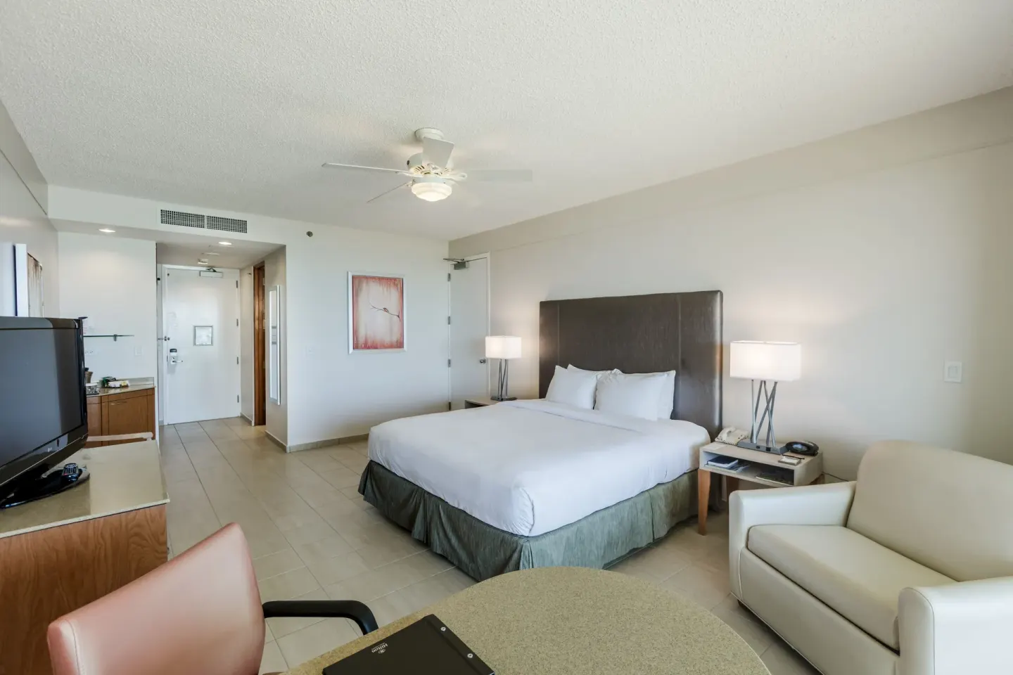 King bed guest room with seating and TV at Hilton Ponce Golf & Casino Resort.