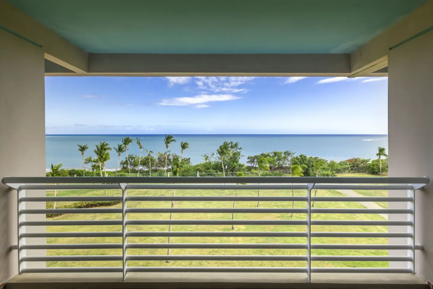 Ocean Tower suite balcony view of lawn, palms, and ocean at Hilton Ponce Golf & Casino Resort.