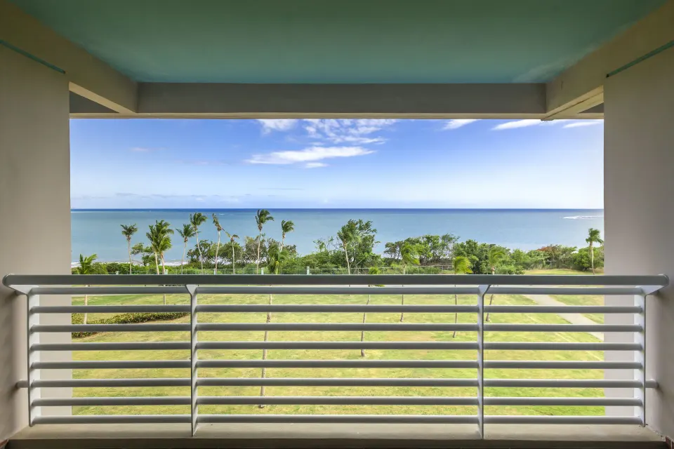 Ocean Tower suite balcony view of lawn, palms, and ocean at Hilton Ponce Golf & Casino Resort.