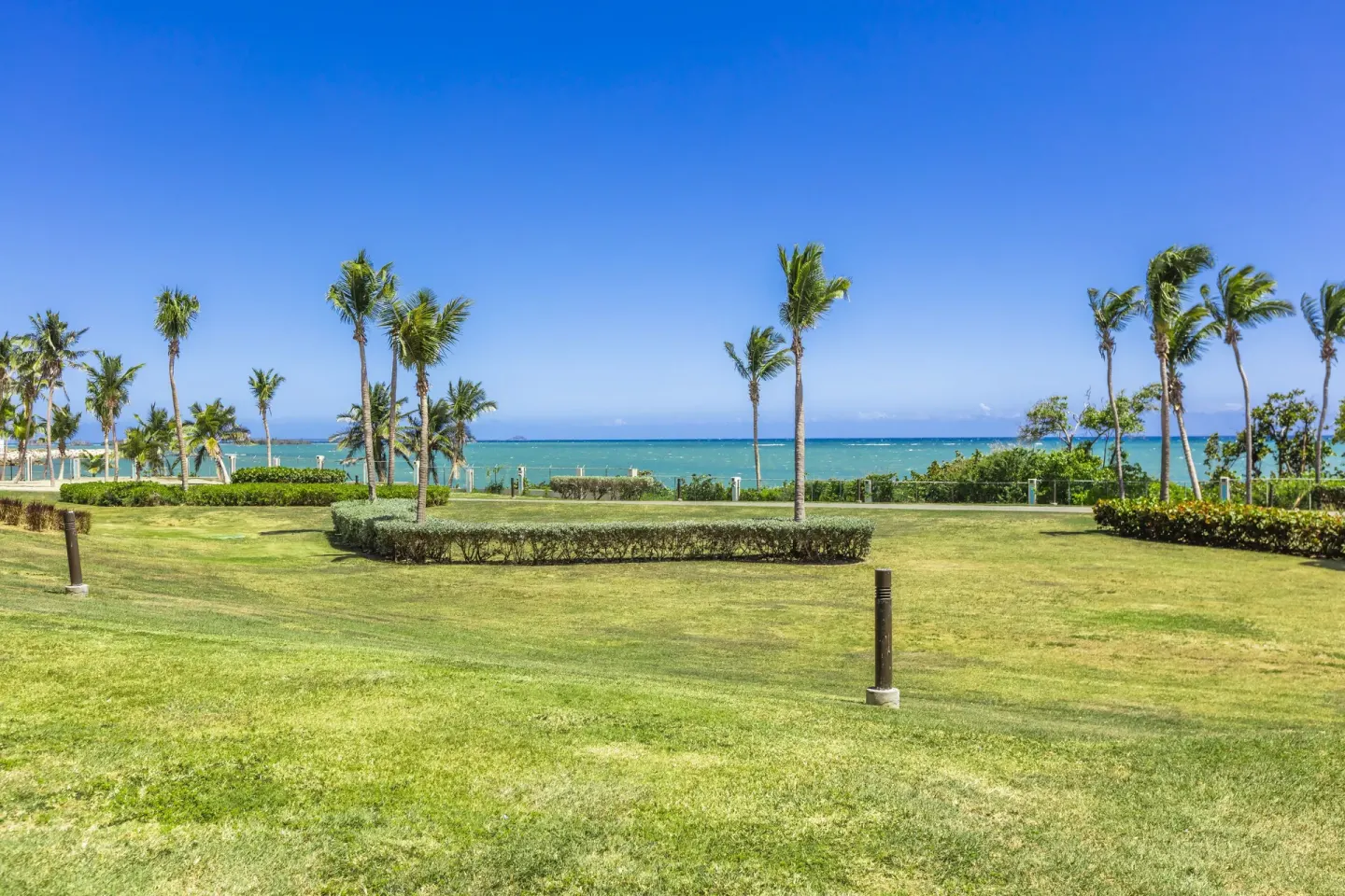 Ocean Tower suite view across lawn and palm trees to the ocean at Hilton Ponce Golf & Casino Resort.