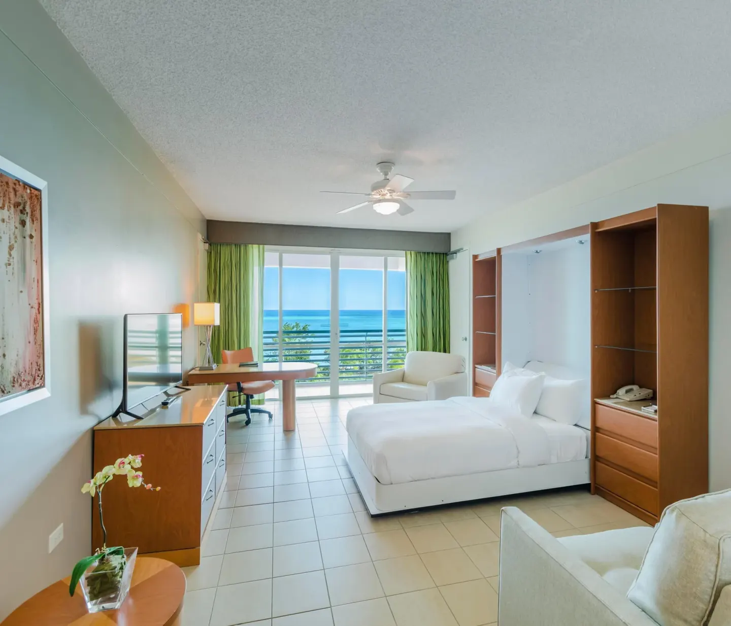 Ocean Tower suite king room with wall bed, seating, desk, and ocean balcony at Hilton Ponce Golf & Casino Resort.