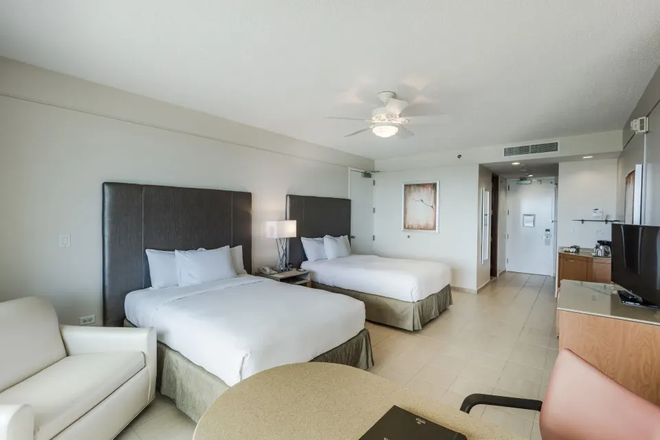 Oceanfront deluxe patio room with two beds and seating at Hilton Ponce Golf & Casino Resort.