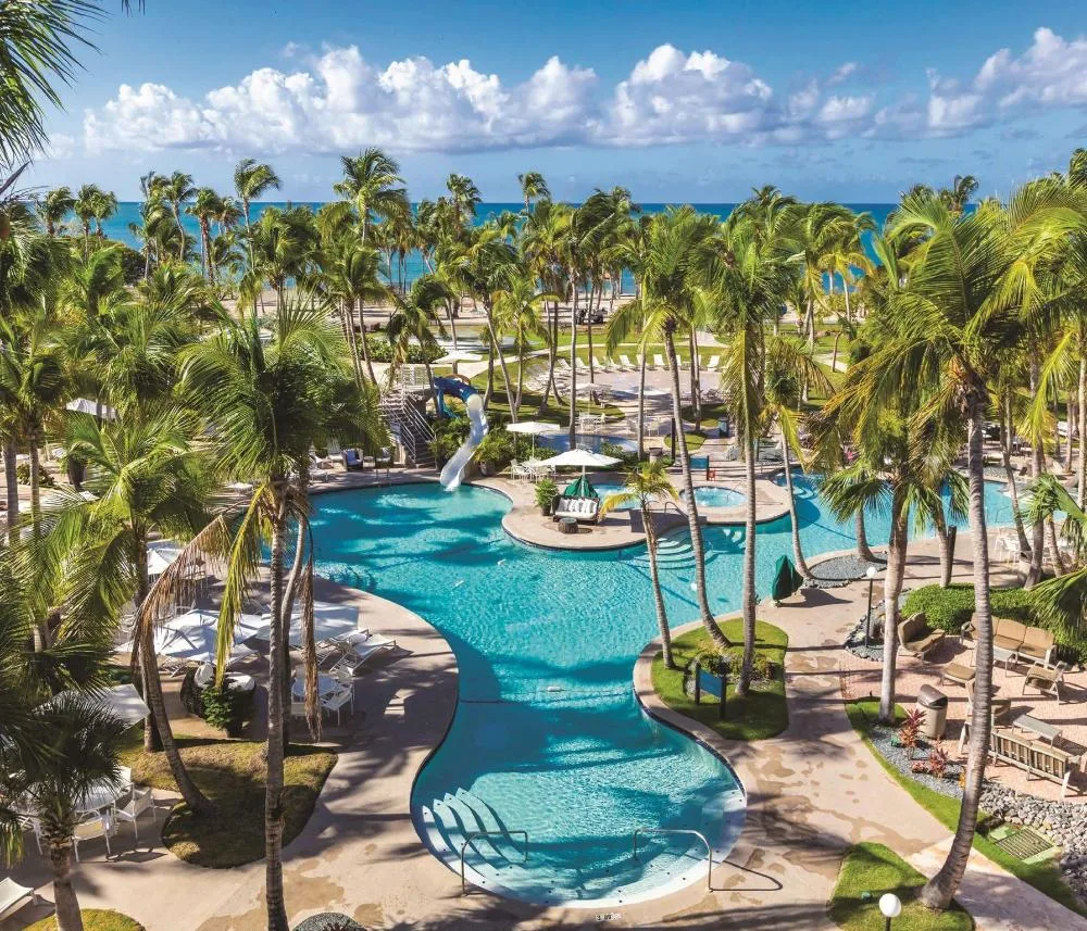 Oceanfront patio room view of pools, palms and the sea at Hilton Ponce Golf & Casino Resort.