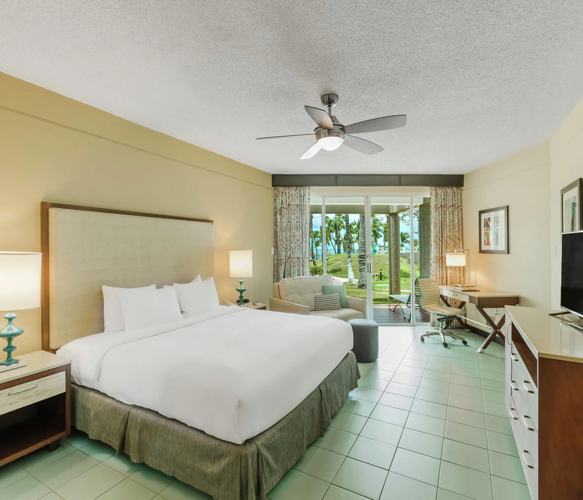 King-bed oceanfront patio room at Hilton Ponce Golf & Casino Resort with patio doors and palm view.