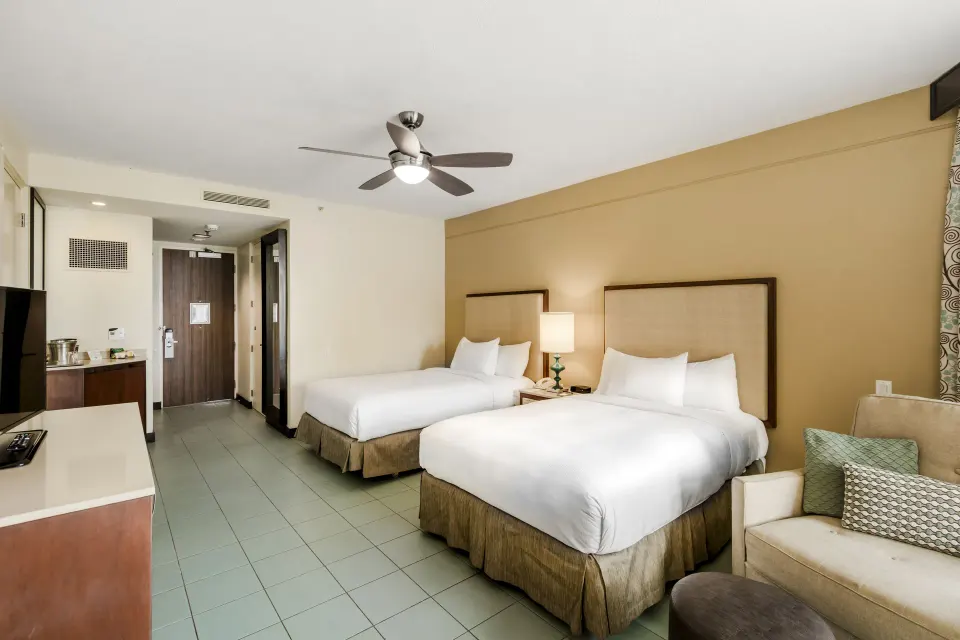 Two-bed oceanfront patio room interior at Hilton Ponce Golf & Casino Resort with seating and entry area.