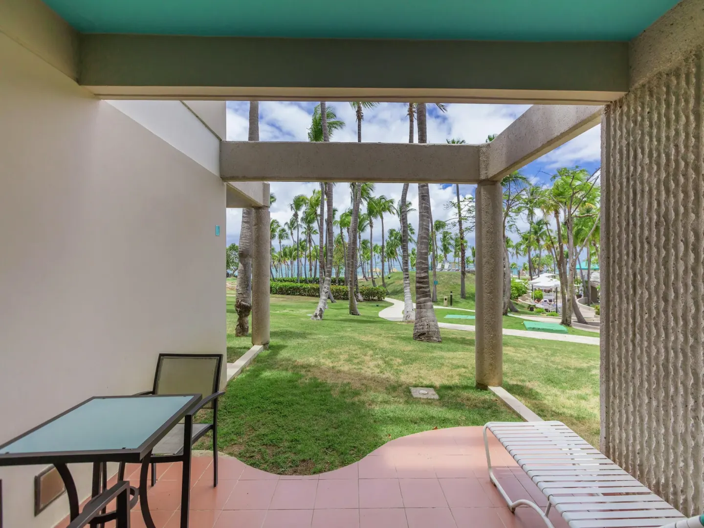 Patio with lawn, palms, and pool area beyond at Hilton Ponce Golf & Casino Resort.