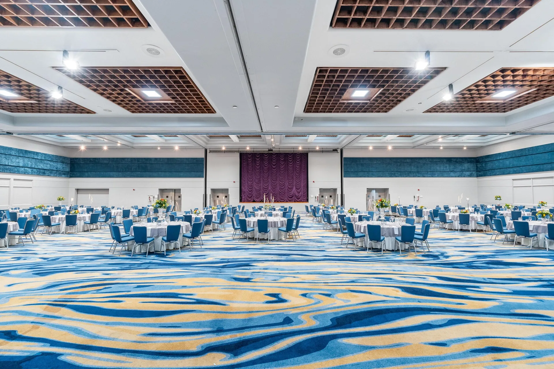 Grand ballroom with round banquet tables and blue patterned carpet at Hilton Ponce Golf & Casino Resort.