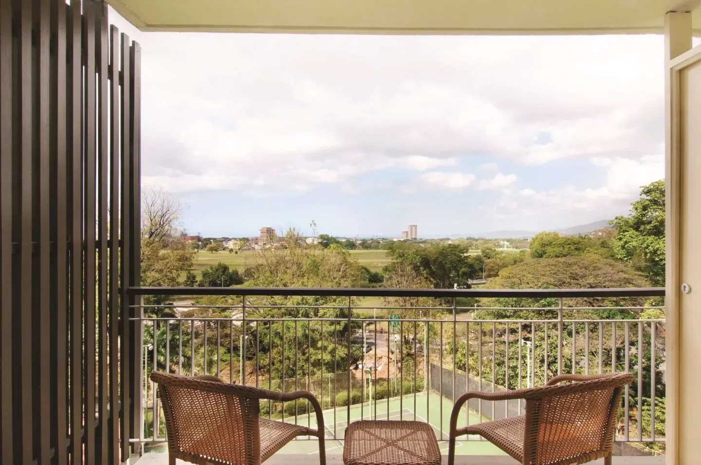Balcony seating overlooks trees and distant city at Hilton Trinidad & Conference Centre.