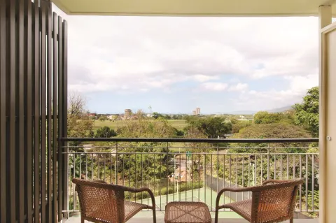 Balcony seating overlooks trees and distant city at Hilton Trinidad & Conference Centre.