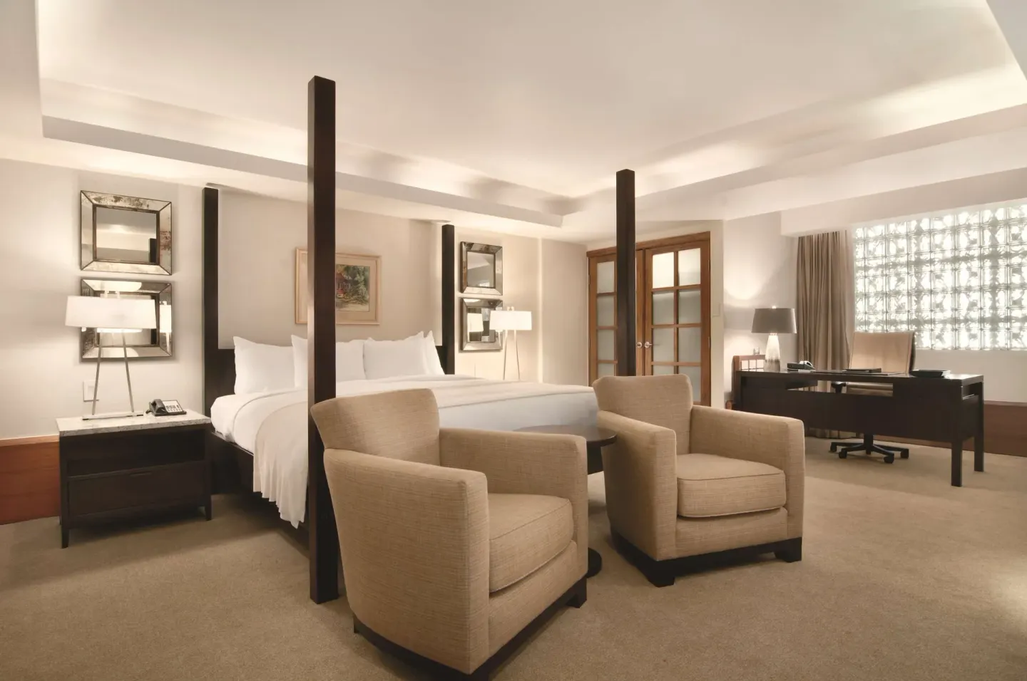 Four-poster king bedroom with seating and desk at Hilton Trinidad & Conference Centre.