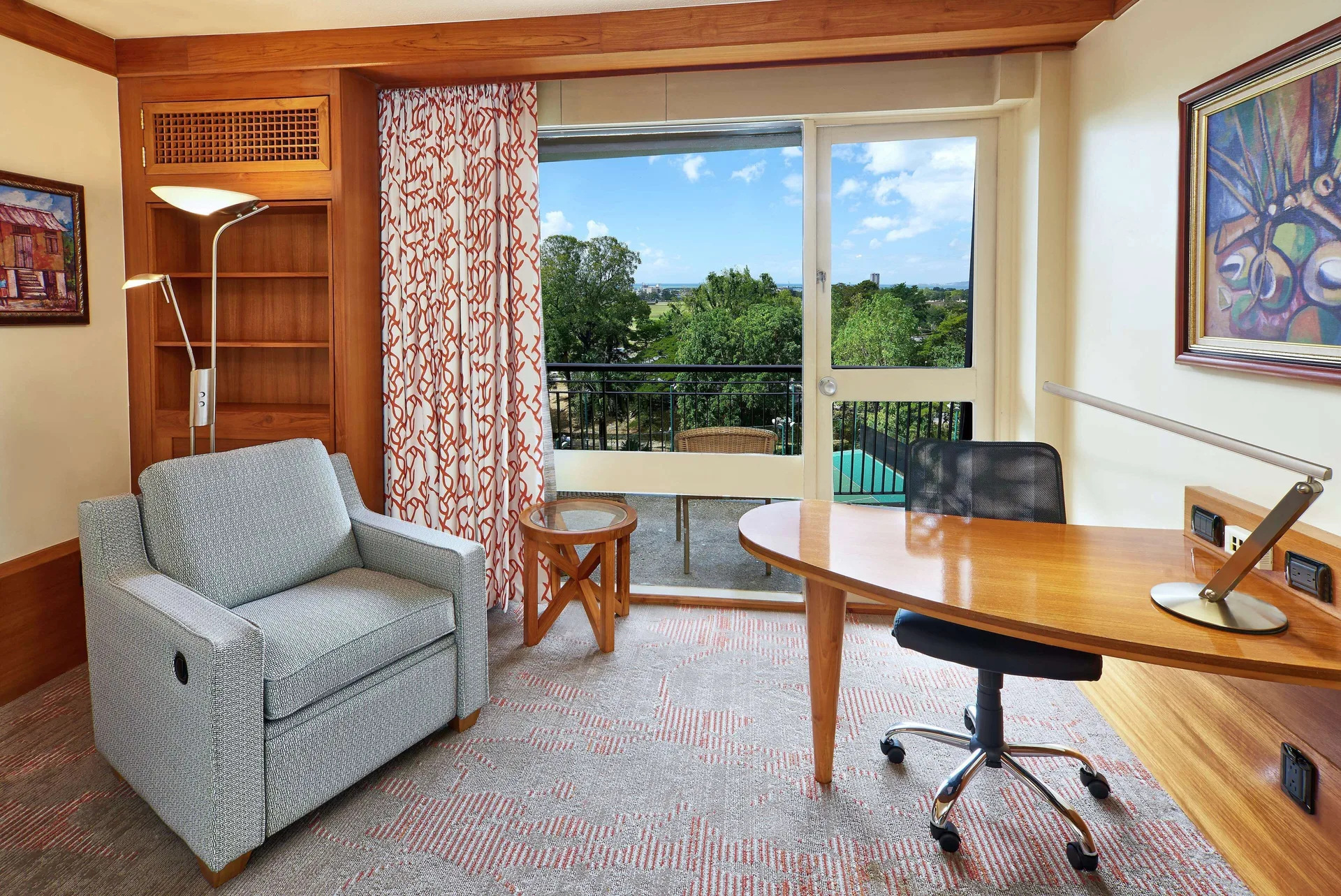 Guest room sitting area with desk and balcony doors at Hilton Trinidad & Conference Centre.