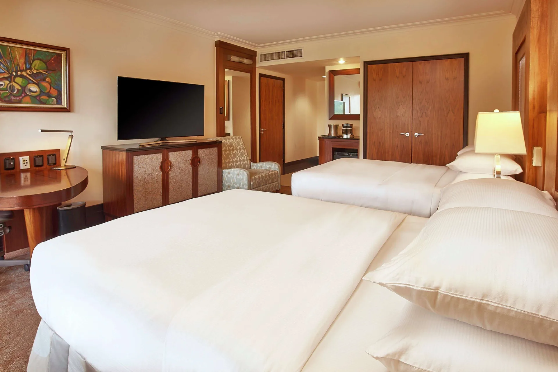Guest room with two beds, desk, and TV cabinet at Hilton Trinidad & Conference Centre.