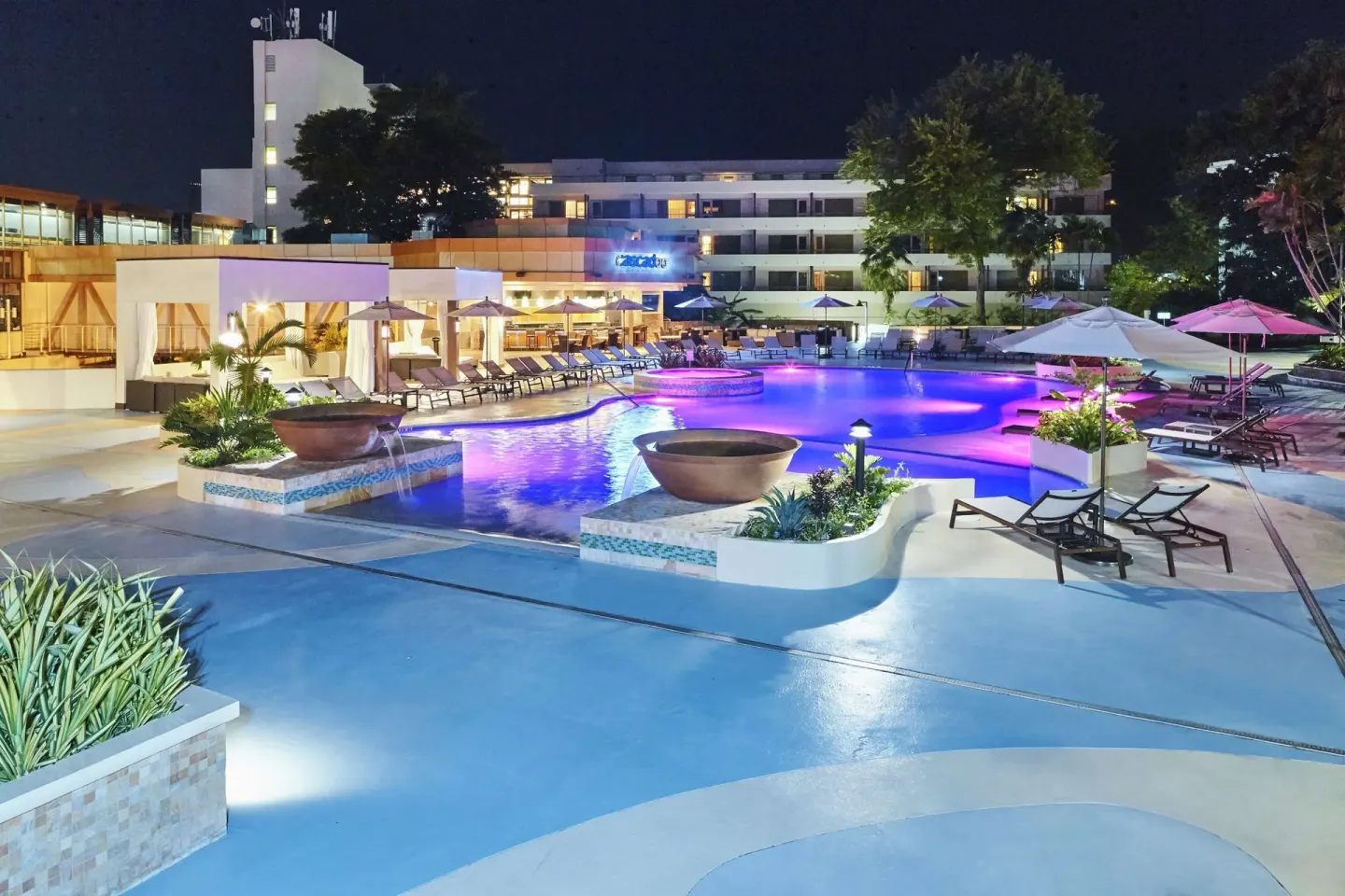 Illuminated pool and deck at night at Hilton Trinidad & Conference Centre.