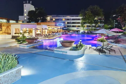 Illuminated pool and deck at night at Hilton Trinidad & Conference Centre.