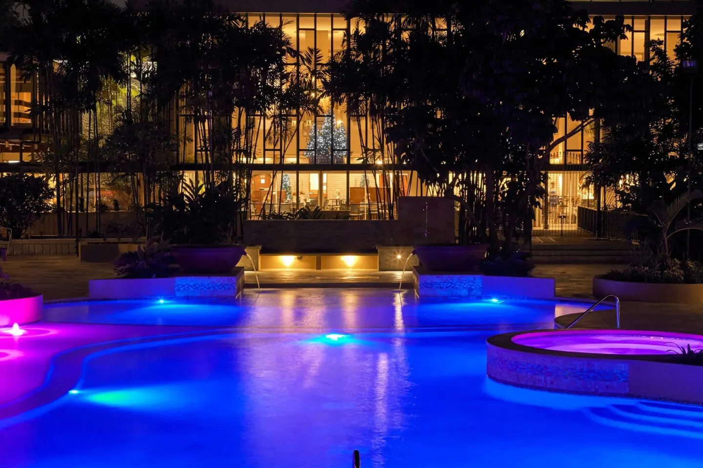 Night-lit pool with colorful underwater lights at Hilton Trinidad & Conference Centre.