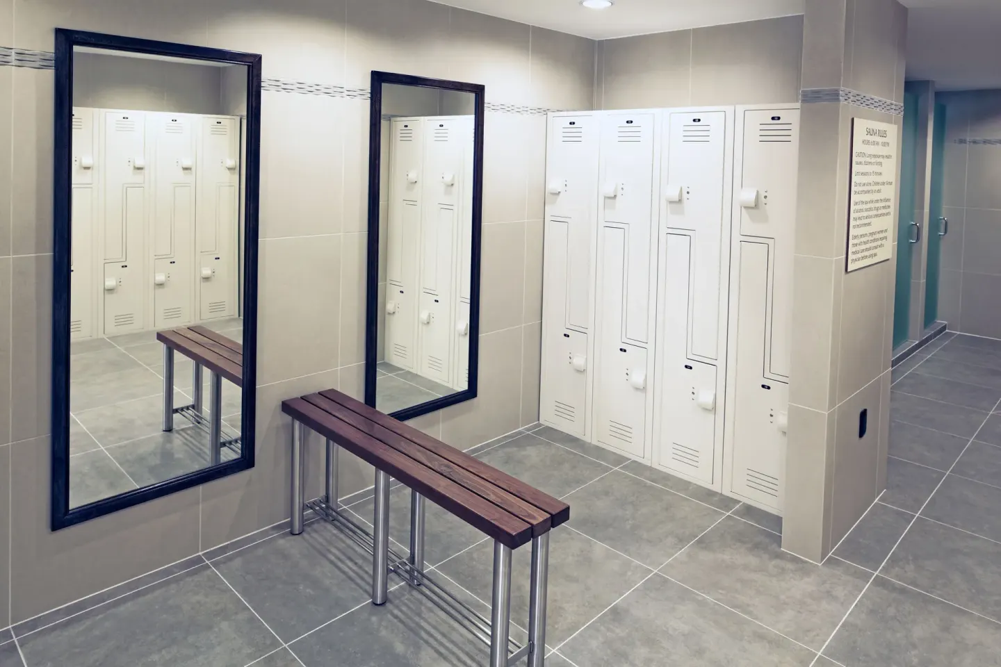 Locker room with white lockers and benches at Hilton Trinidad & Conference Centre.
