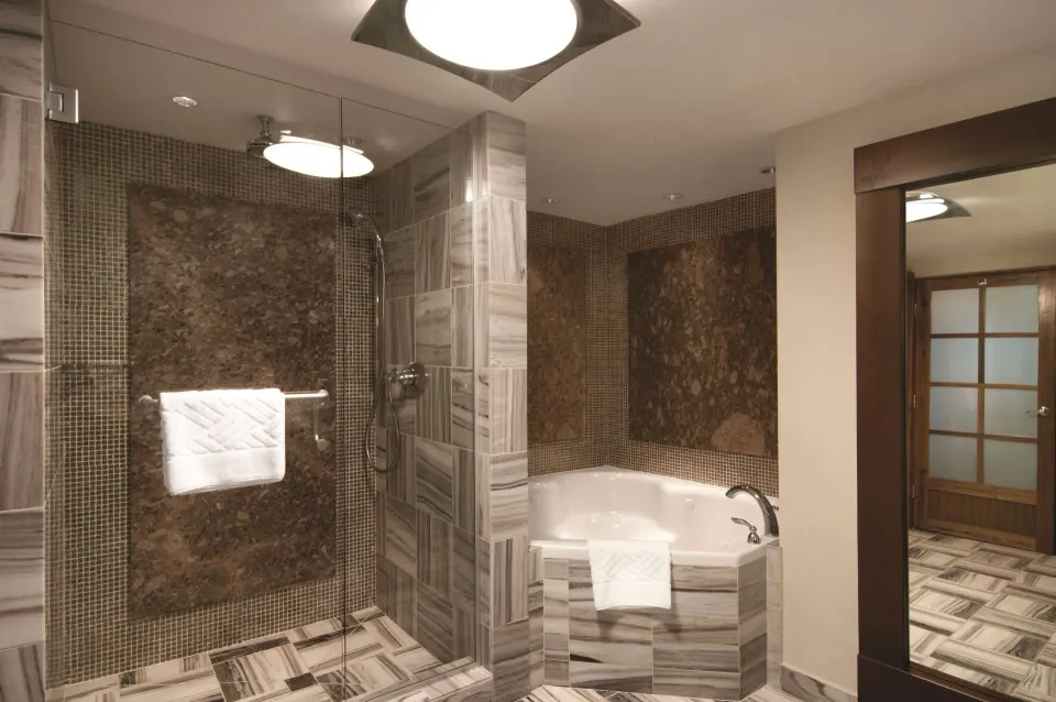 Marble bathroom with glass shower and bathtub at Hilton Trinidad & Conference Centre.