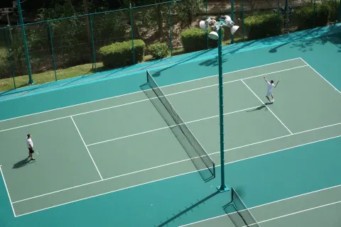 Tennis players on an outdoor court at Hilton Trinidad & Conference Centre.