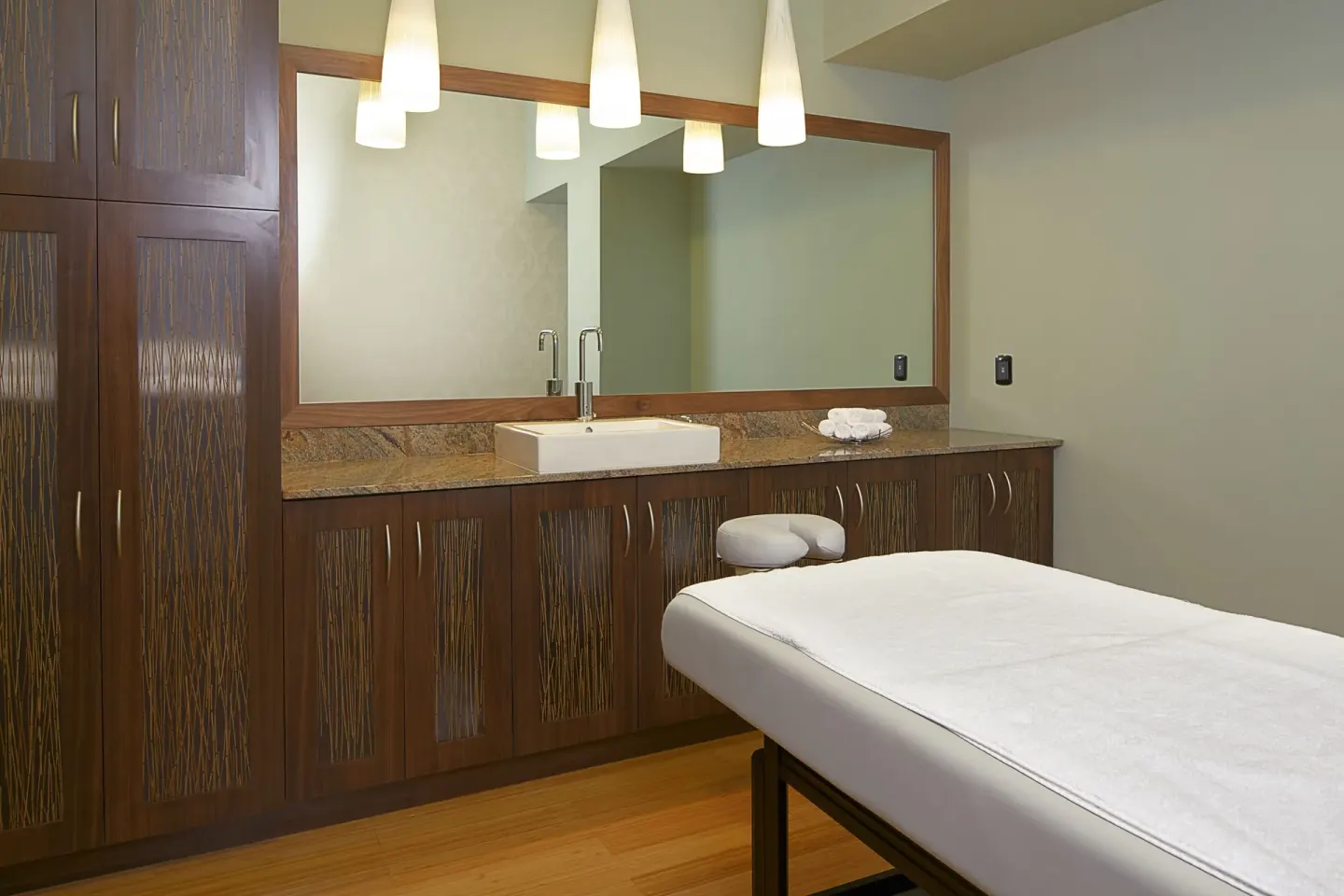 Spa treatment room with massage table and vanity at Hilton Trinidad & Conference Centre.