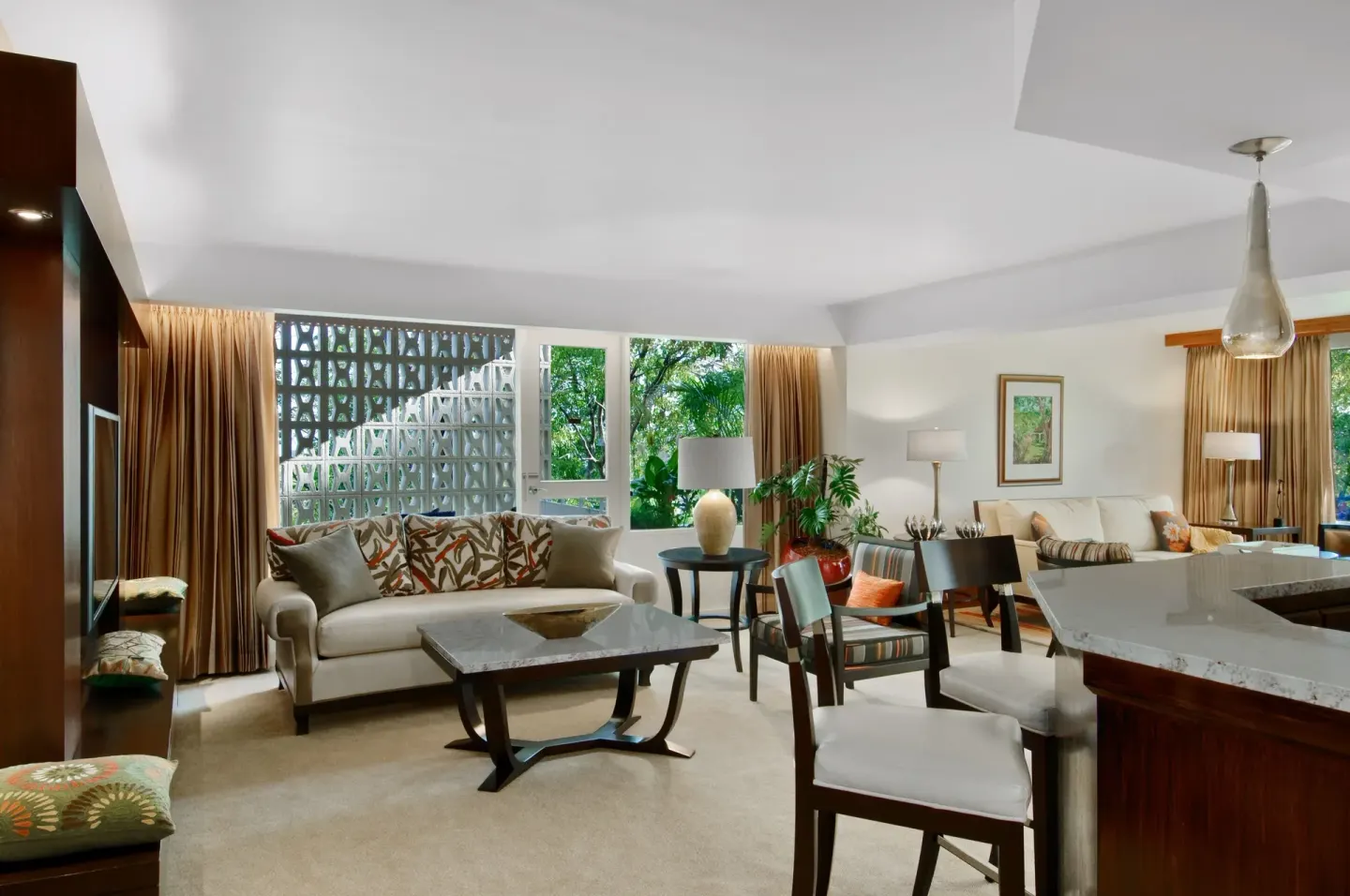 Suite living area with sofa, dining table, and kitchenette at Hilton Trinidad & Conference Centre.