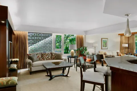 Suite living area with sofa, dining table, and kitchenette at Hilton Trinidad & Conference Centre.