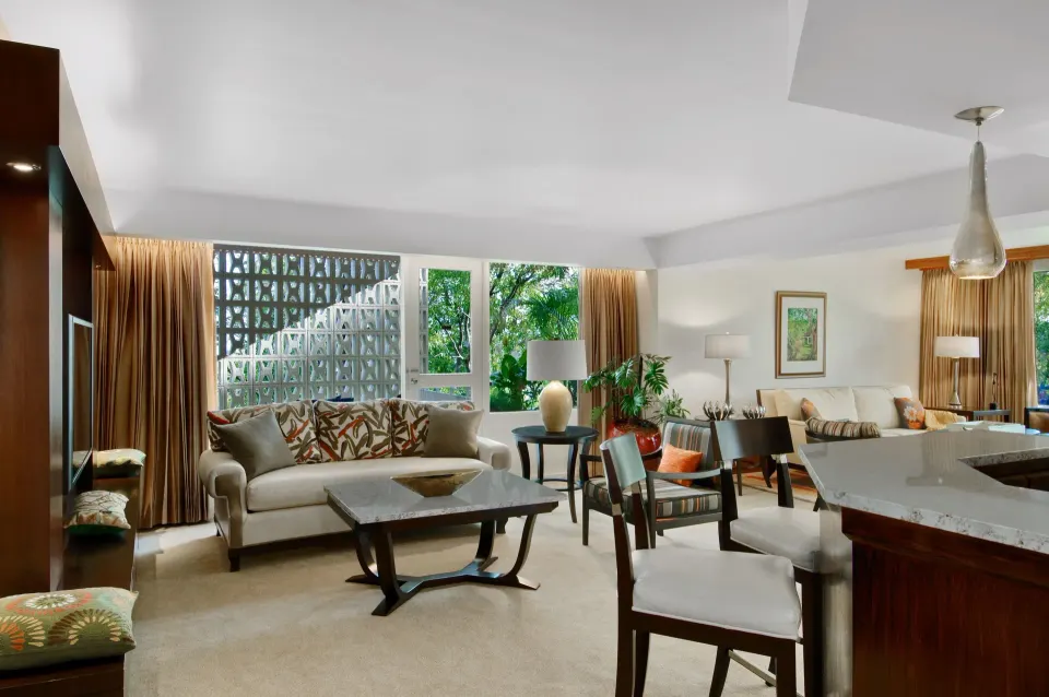 Suite living area with sofa, dining table, and kitchenette at Hilton Trinidad & Conference Centre.
