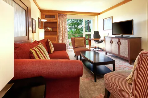 Living room with red sofa, desk, and TV at Hilton Trinidad & Conference Centre.