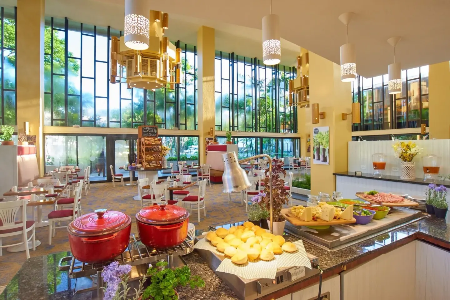 Breakfast buffet station with hot dishes and dining tables at Hilton Trinidad & Conference Centre.