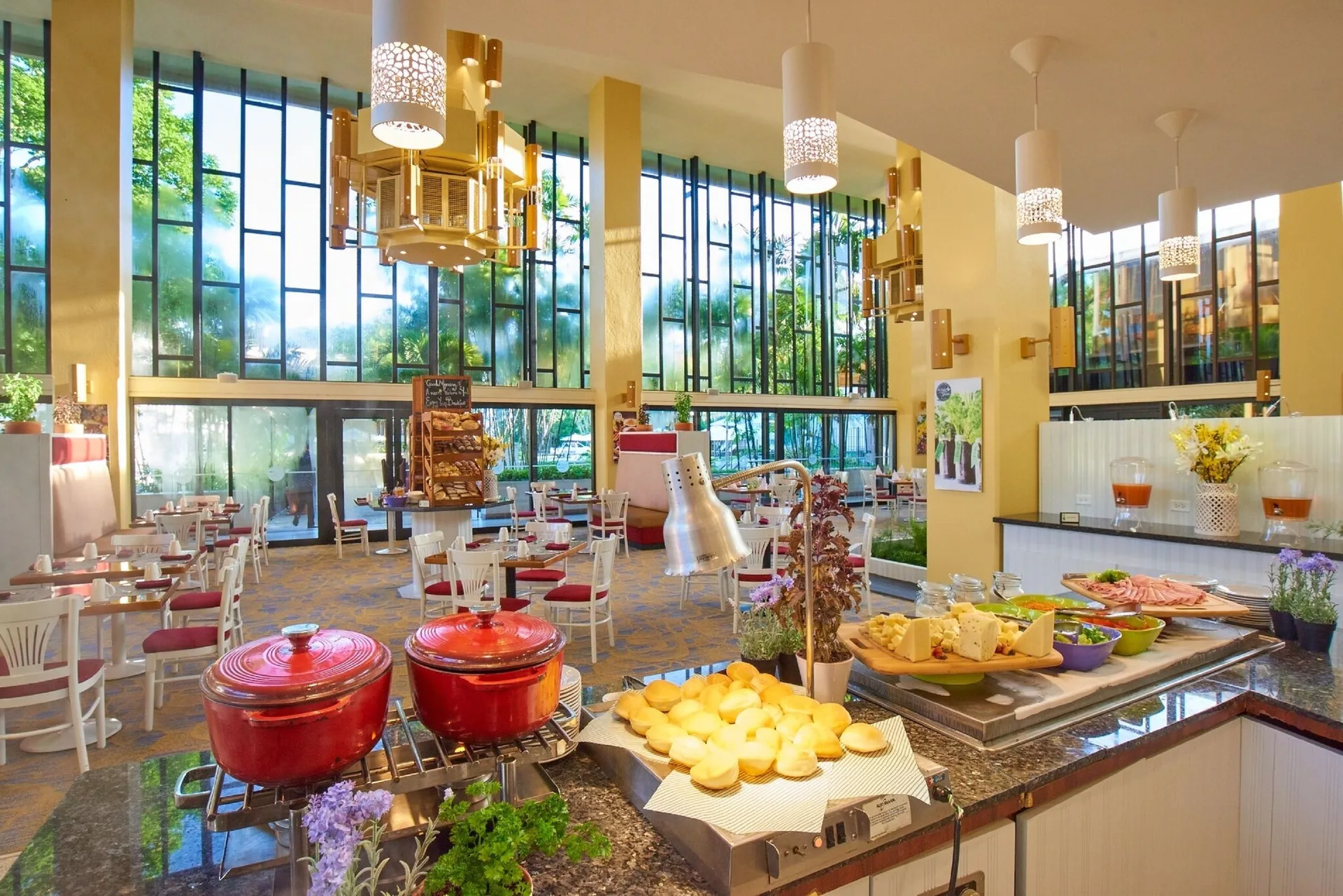 Breakfast buffet station with hot dishes and dining tables at Hilton Trinidad & Conference Centre.