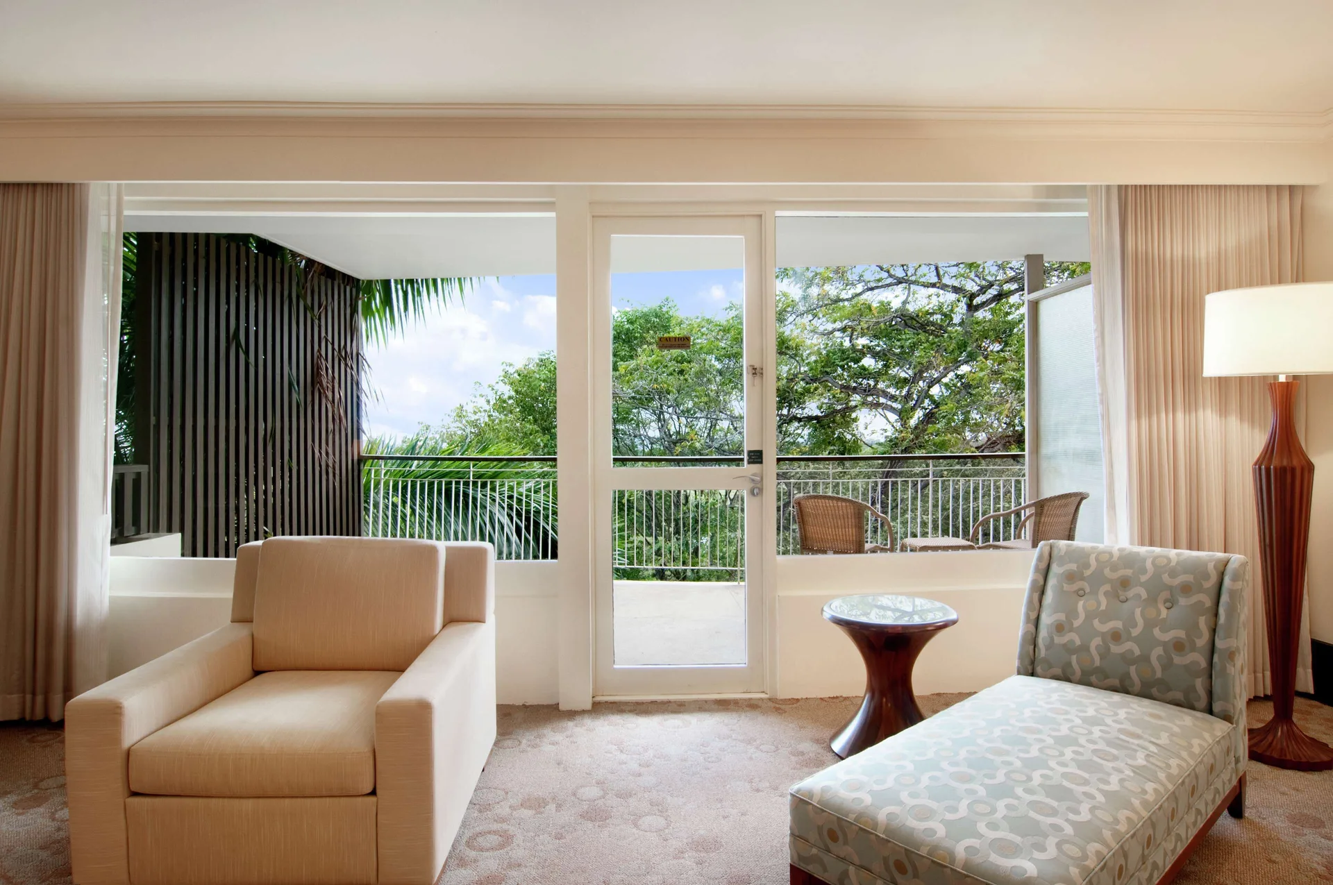 Deluxe Studio Suite seating area with balcony and trees at Hilton Trinidad & Conference Centre.