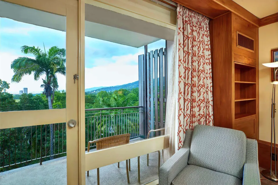 Executive Room balcony doors and lounge chair at Hilton Trinidad & Conference Centre.
