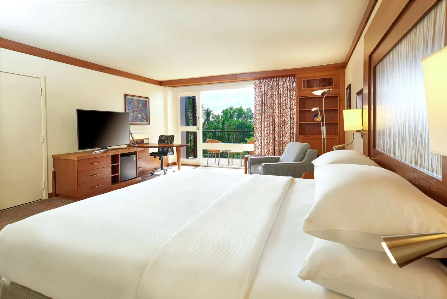 Executive Room king bed facing TV and balcony at Hilton Trinidad & Conference Centre.