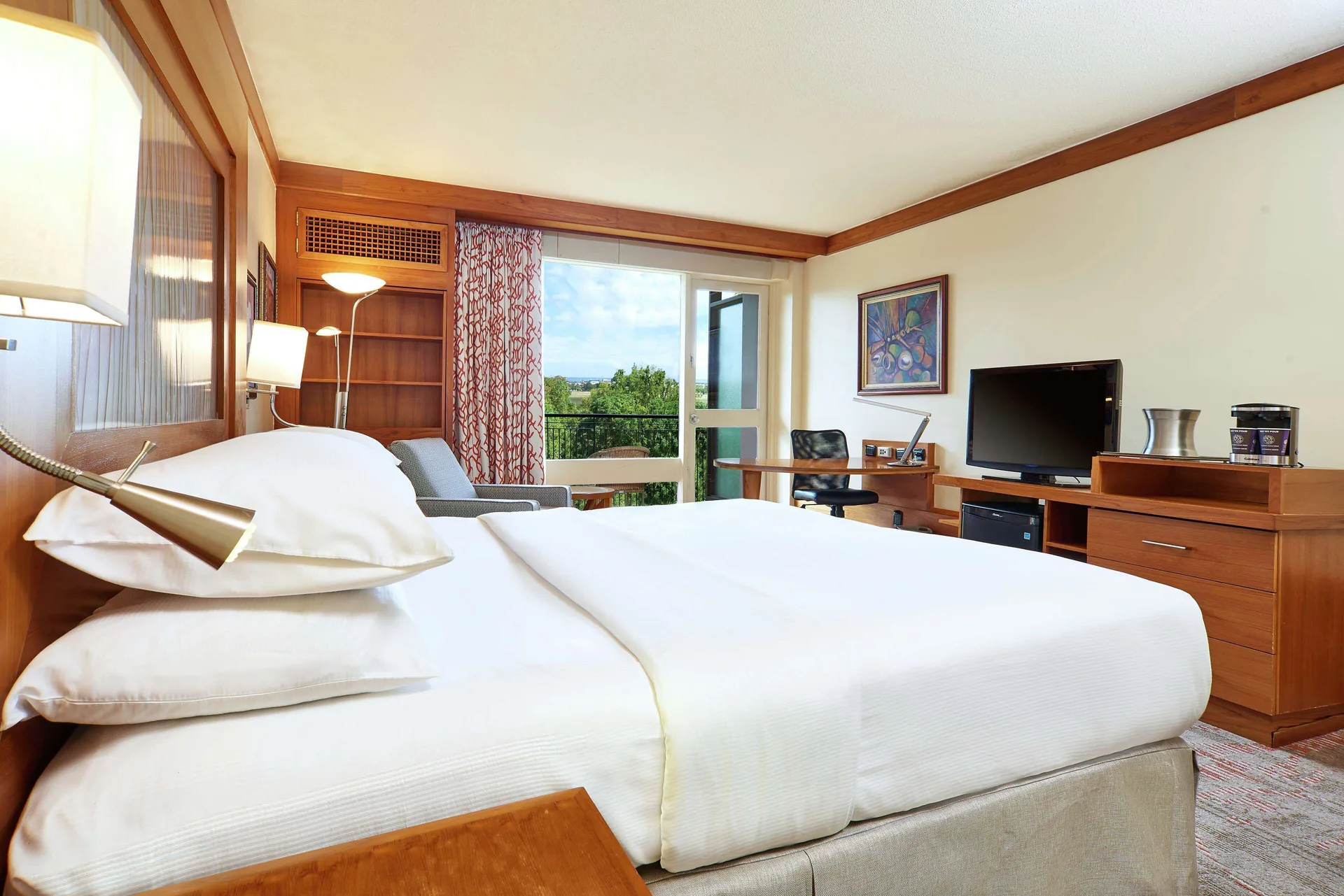 Executive Room king bed, TV, and work area at Hilton Trinidad & Conference Centre.