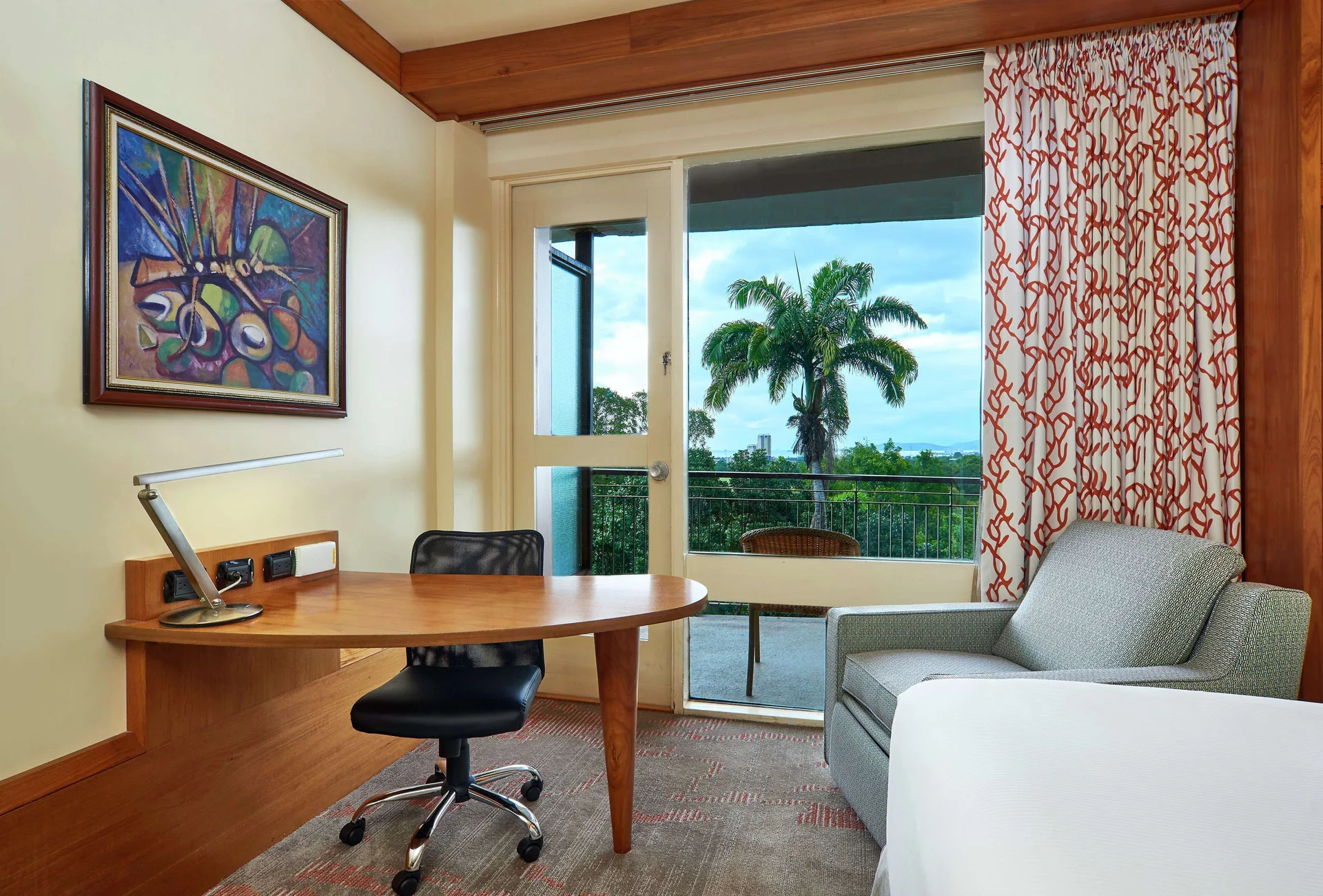 Executive Room desk, armchair, and balcony view at Hilton Trinidad & Conference Centre.