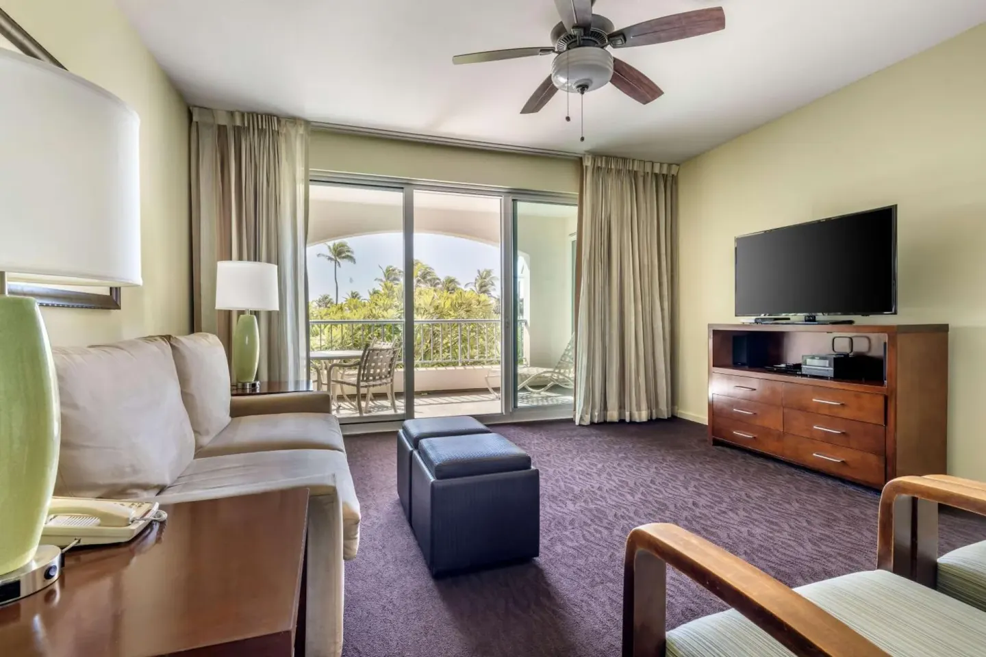 Living room with sofa, TV, and balcony at Hilton Vacation Club The Point At Poipu Kauai.