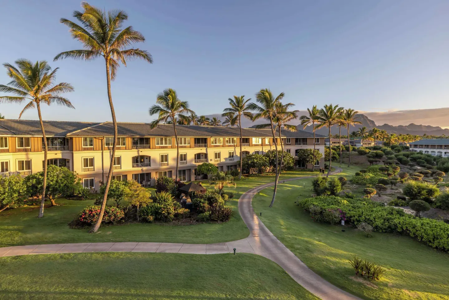 Sunlit resort buildings and lawns at Hilton Vacation Club The Point At Poipu Kauai.