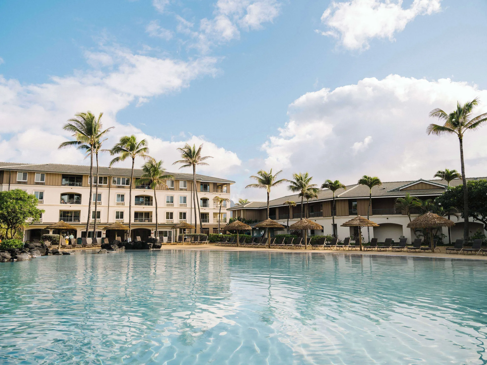 Resort pool with palm trees and buildings at Hilton Vacation Club The Point At Poipu Kauai.