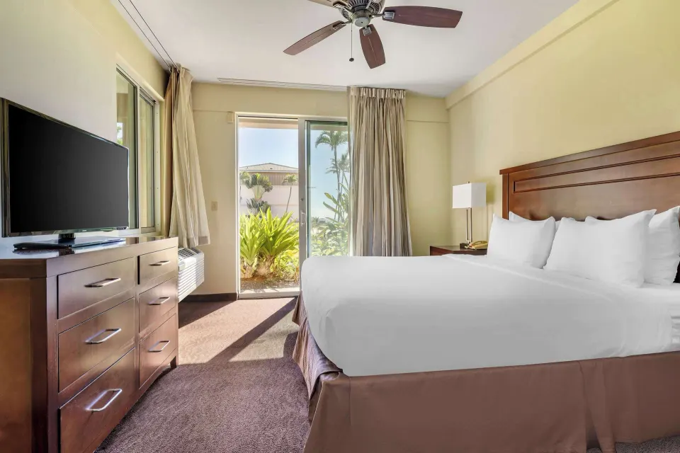 King bedroom with TV and patio door at Hilton Vacation Club The Point At Poipu Kauai.