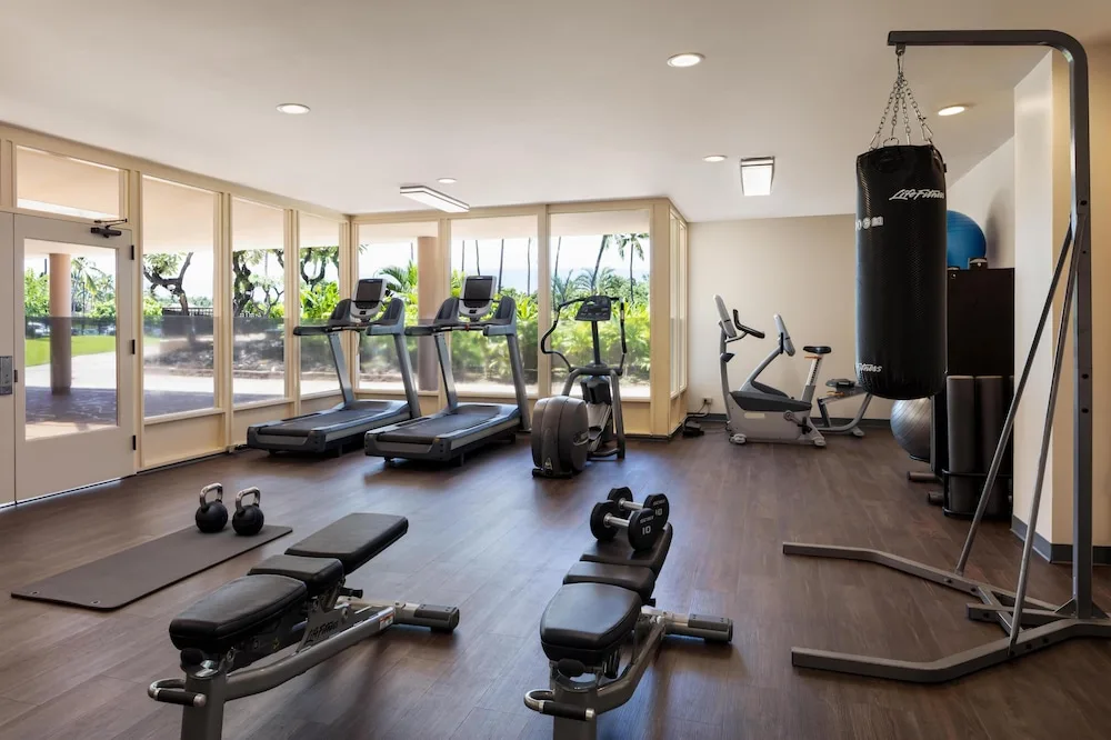 Fitness room with cardio machines, benches, weights, and a punching bag at Hilton Waikoloa Village.