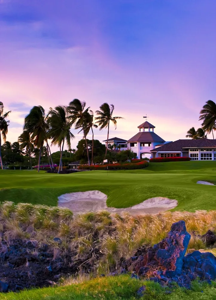 Golf green, sand bunkers, palms, and clubhouse at Hilton Waikoloa Village.