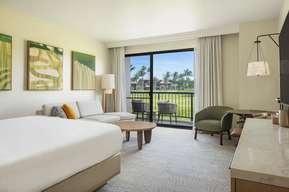 King bed guest room with sofa and balcony view at Hilton Waikoloa Village.