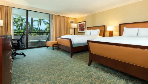 Two-bed guest room with balcony and palm views at Hilton Waikoloa Village.