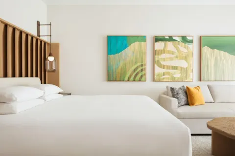 King guest room with sofa and abstract wall art at Hilton Waikoloa Village.
