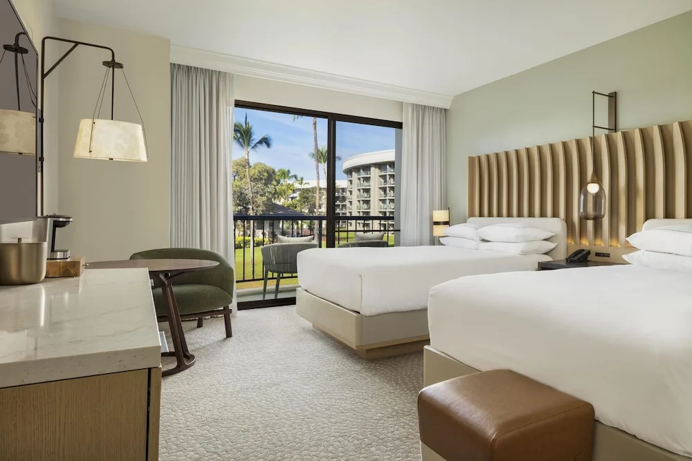 Two queen beds with balcony, table and coffee station at Hilton Waikoloa Village.