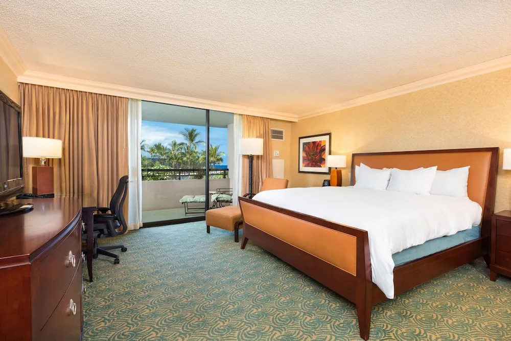 King bed guest room with work desk and balcony at Hilton Waikoloa Village.