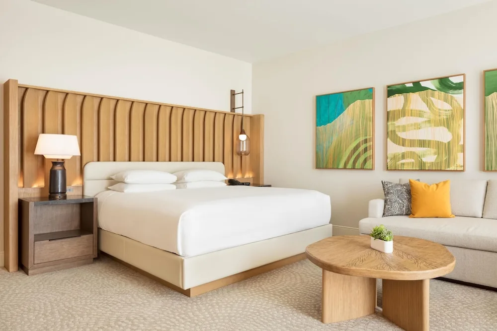 King bed guest room with wood headboard and sofa at Hilton Waikoloa Village.