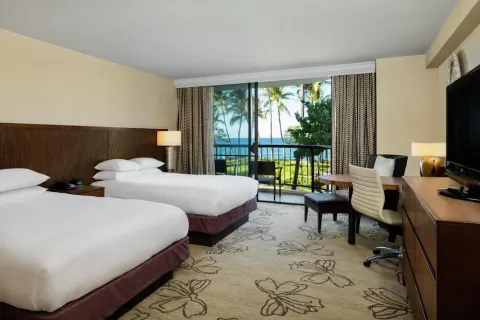 Two-bed guest room with ocean view balcony and work desk at Hilton Waikoloa Village.